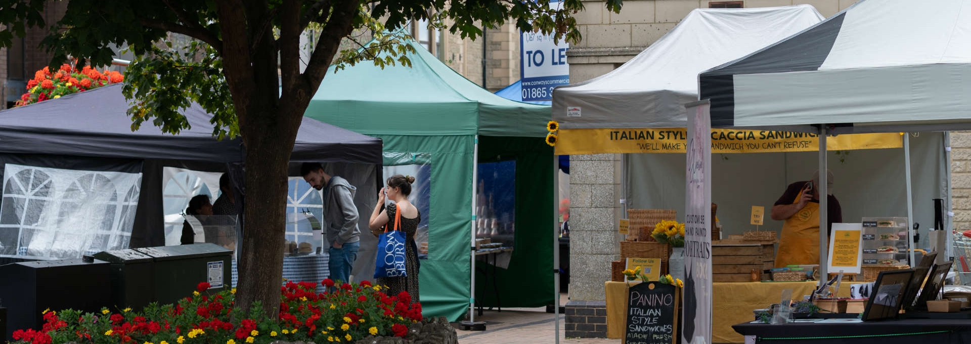 Artisan market stalls in Kidlington with vendors and visitors under tents and trees.